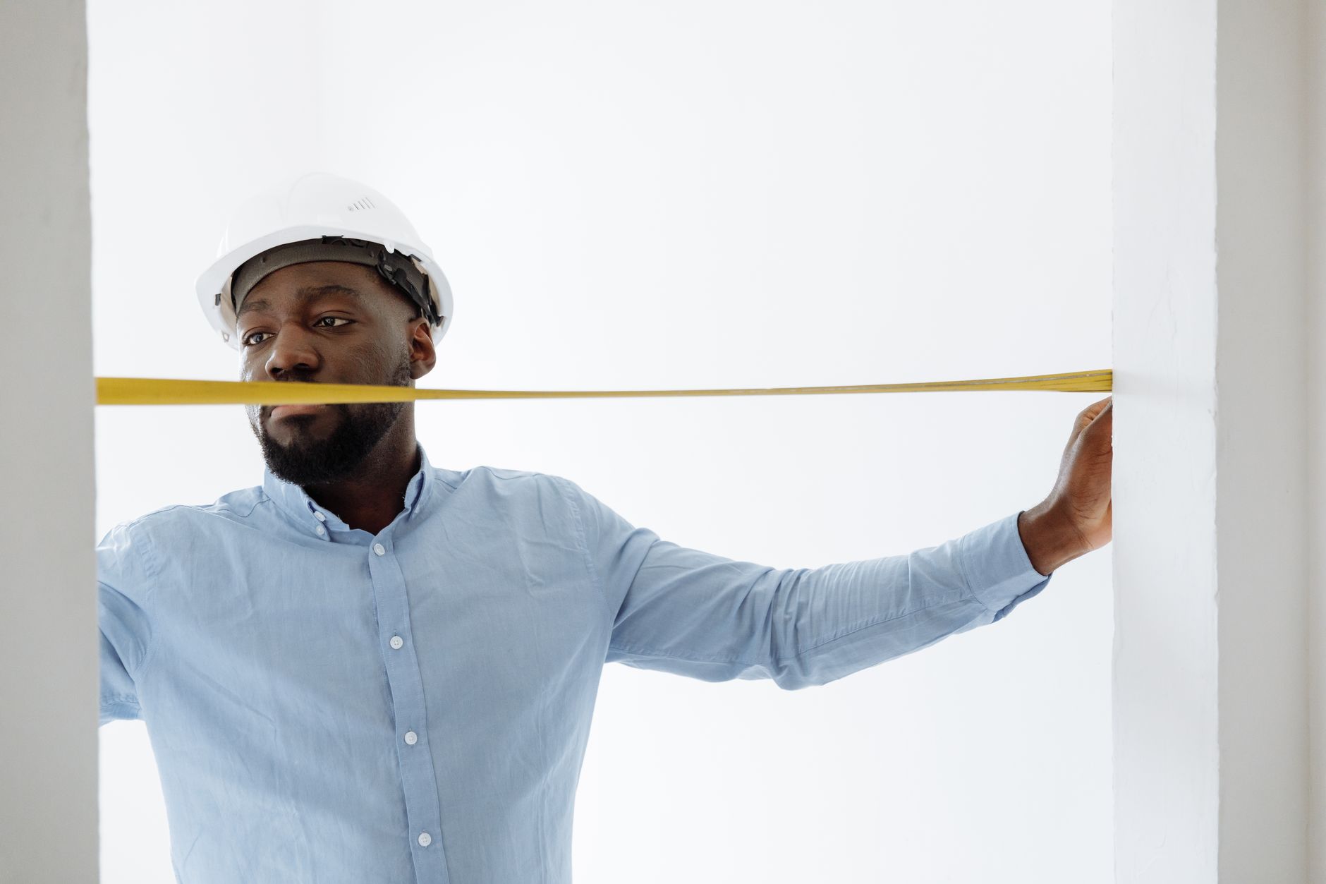 Engineer measuring an industrial machine with a tape measure before ordering a custom cover
