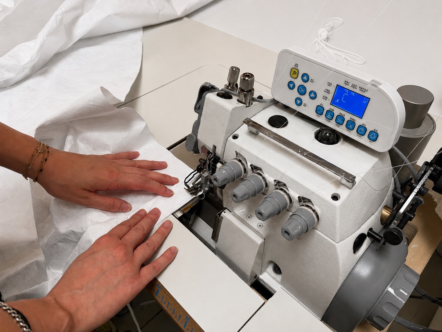 Couture d'un tissu technique blanc à l'atelier RCC, fabrication d'une protection de câbles de robot